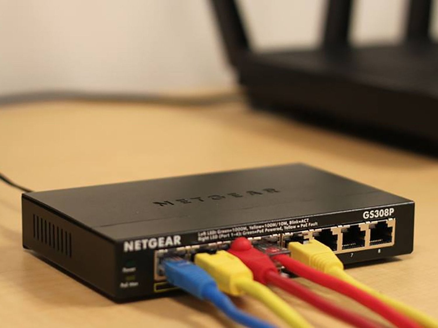 Un router Netgear con cables azules, amarillos y rojos, incluyendo una conexión Ethernet.